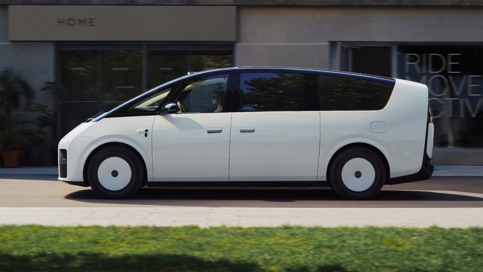 Side view of the next-generation Li Mega electric MPV driving past storefronts.