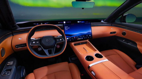 Arcfox Alpha T7 cockpit with orange upholstery, a two-tone steering wheel, a large central touchscreen and a center console with 2 cupholders.