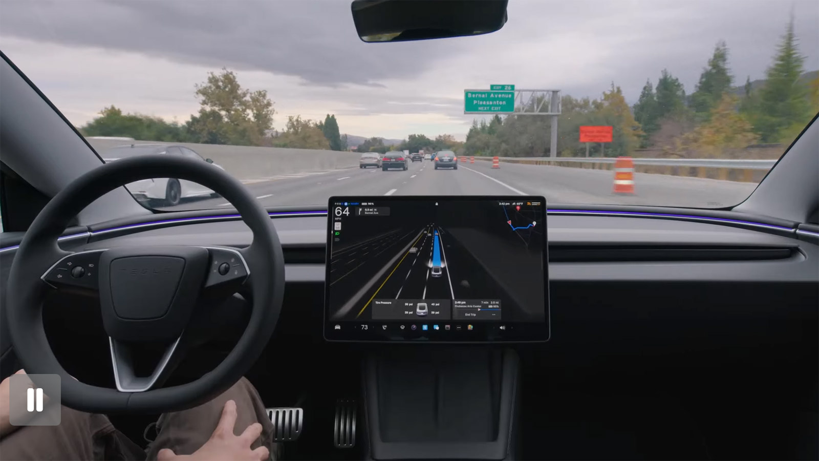 A Tesla using FSD Supervised on a highway, with the center touchscreen displaying driving visualization and navigation information.