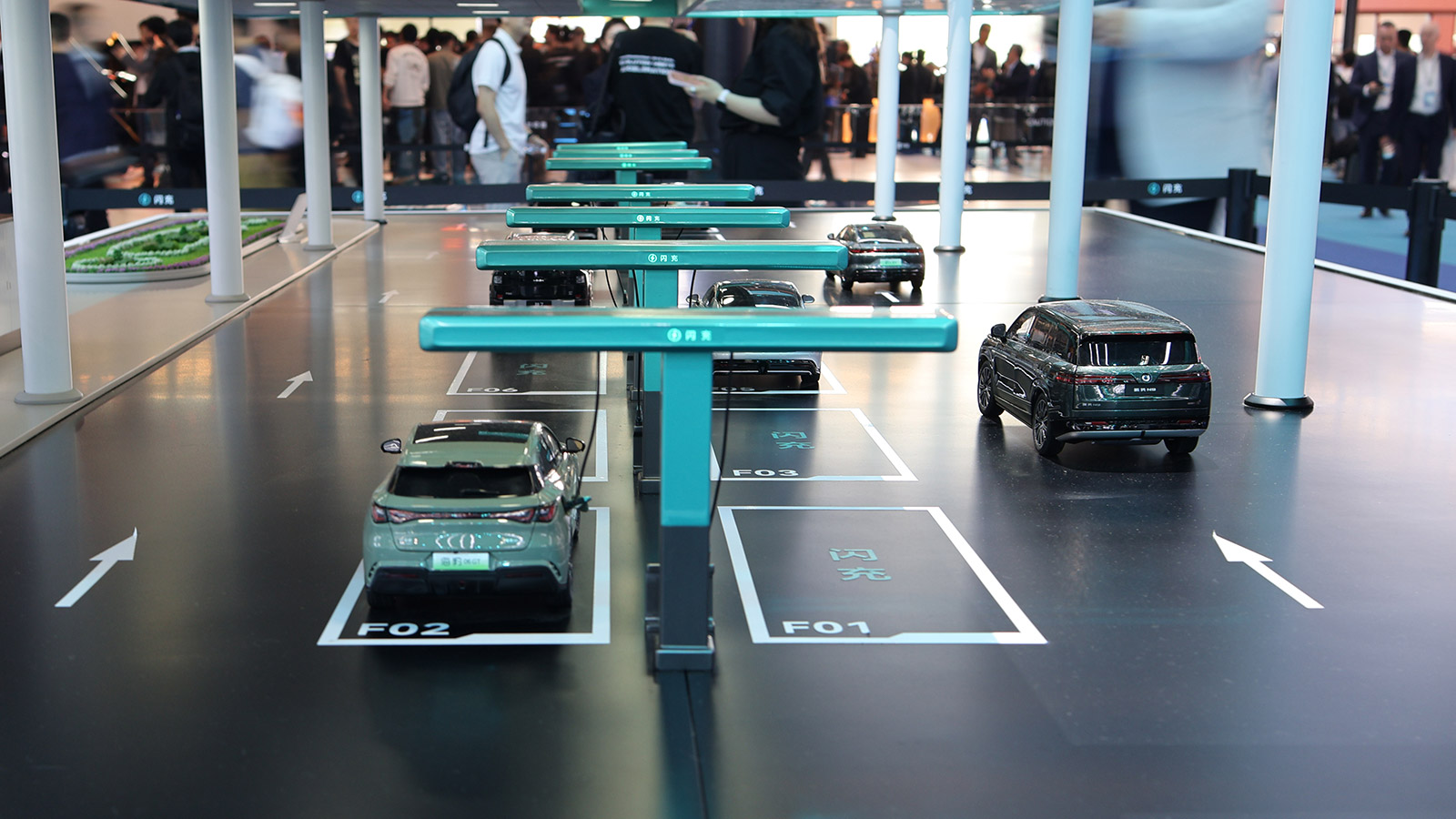 A scale model of a BYD flash charging station with several electric vehicle models on display at the 2026 Beijing auto show.
