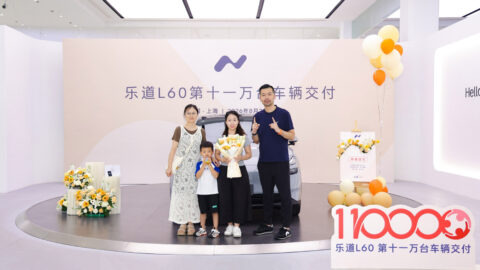 L60 recipients and Onvo representatives pose with flowers in front of the milestone vehicle at a delivery ceremony.