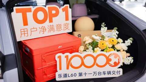 Flowers, gifts and milestone signs arranged in the open cargo area of an Onvo L60 during a delivery ceremony.