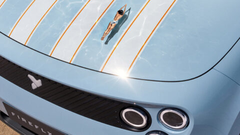 Close-up of the Nio Firefly Club Spiaggia’s striped blue hood, with a swimmer reflected across its surface.
