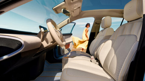 Interior of the Nio Firefly Club Spiaggia with light-colored seats, orange stitching and a panoramic glass roof.