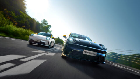 Black and white GWM Ora 5 Sport vehicles driving side by side on a winding road.