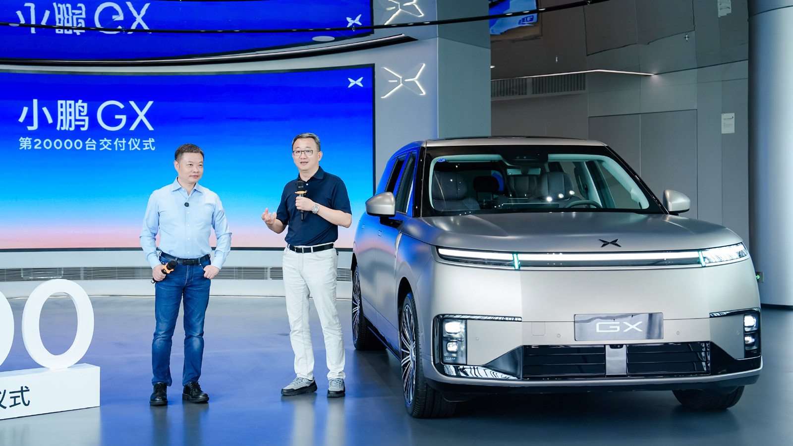 Xpeng chairman and CEO He Xiaopeng and Bosch Huayu Steering Systems general manager Bu Xinwen speak beside a silver Xpeng GX at a ceremony marking 20,000 deliveries of the model.