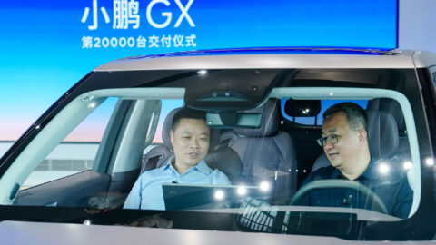 He Xiaopeng sits at the wheel of an Xpeng GX while Bu Xinwen sits in the front passenger seat during the model’s delivery milestone ceremony.