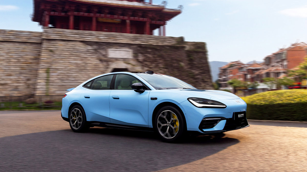 A light blue Geely Galaxy TT electric sedan driving past a traditional Chinese city wall.