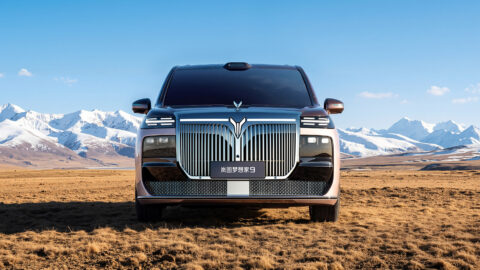 Front view of the Voyah Dream 9 against snow-covered mountains, showing its chrome grille and raised hood ornament.