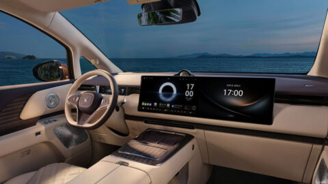 Driver-focused view of the Voyah Dream 9 cabin showing its wide dual-screen display, steering wheel and wood-trimmed center console.