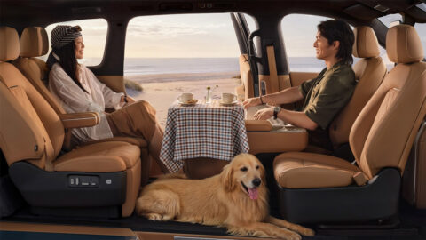 2 people sit facing each other across a table inside a Xiaomi Sky Nomad N90 Max, with a golden retriever on the floor.