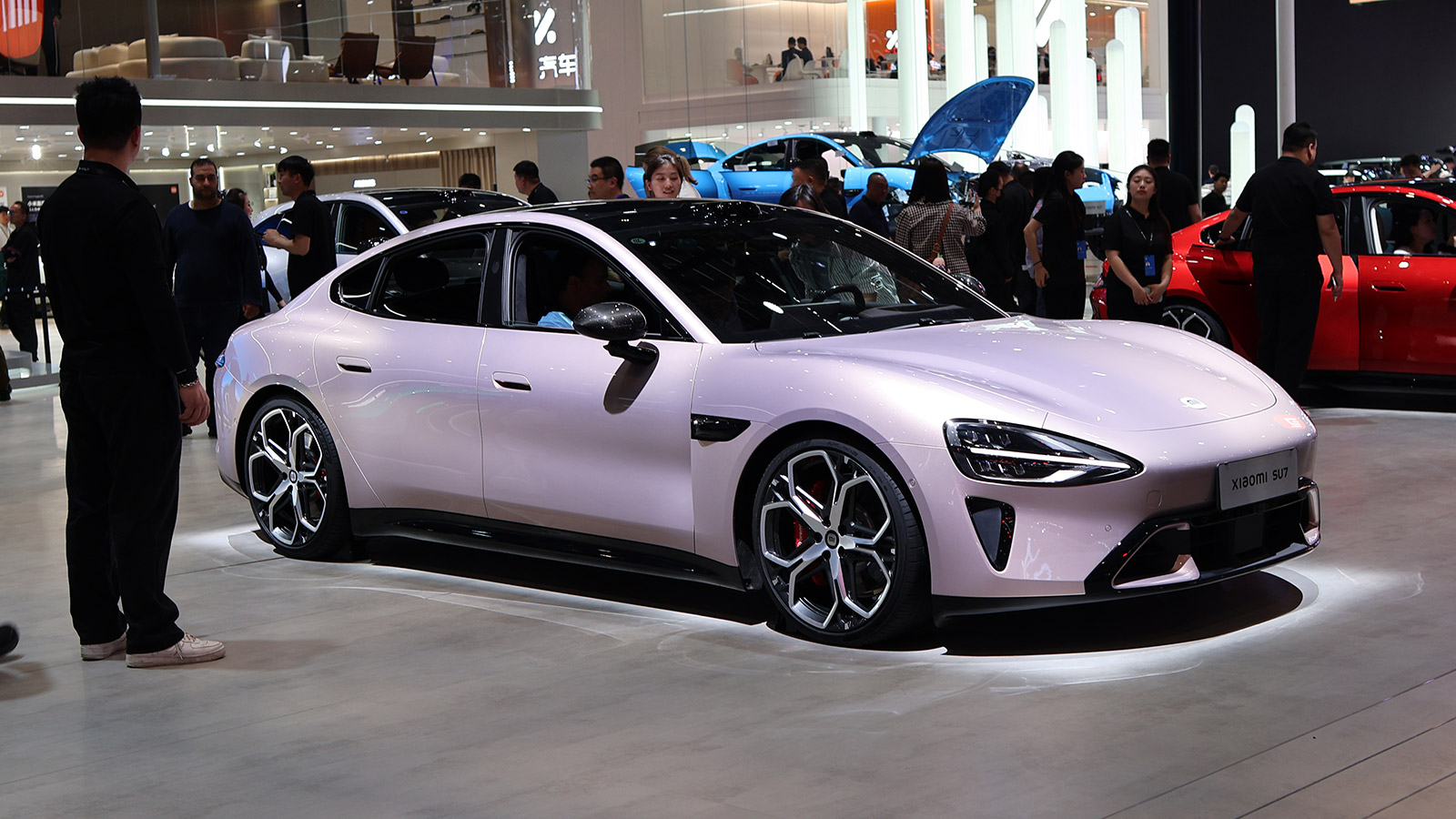 Light purple Xiaomi SU7 electric sedan displayed at the Beijing auto show in April 2026, viewed from the front and side.