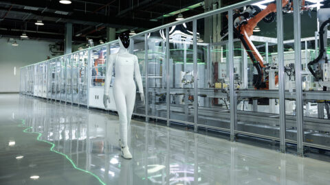 Xpeng's Iron humanoid robot walks alongside automated manufacturing equipment at the company's production facility.