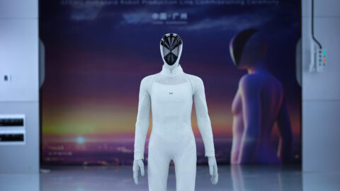 Xpeng's Iron humanoid robot stands in front of a backdrop marking the production line commissioning.