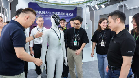 He Xiaopeng and Xpeng staff gather around an Iron humanoid robot during the production line commissioning event.