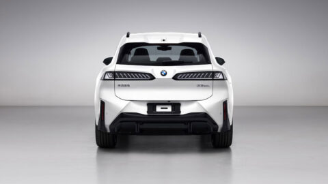 Rear view of a white BMW Neue Klasse iX3 30L, showing its taillights, roof spoiler and BMW Brilliance badging.