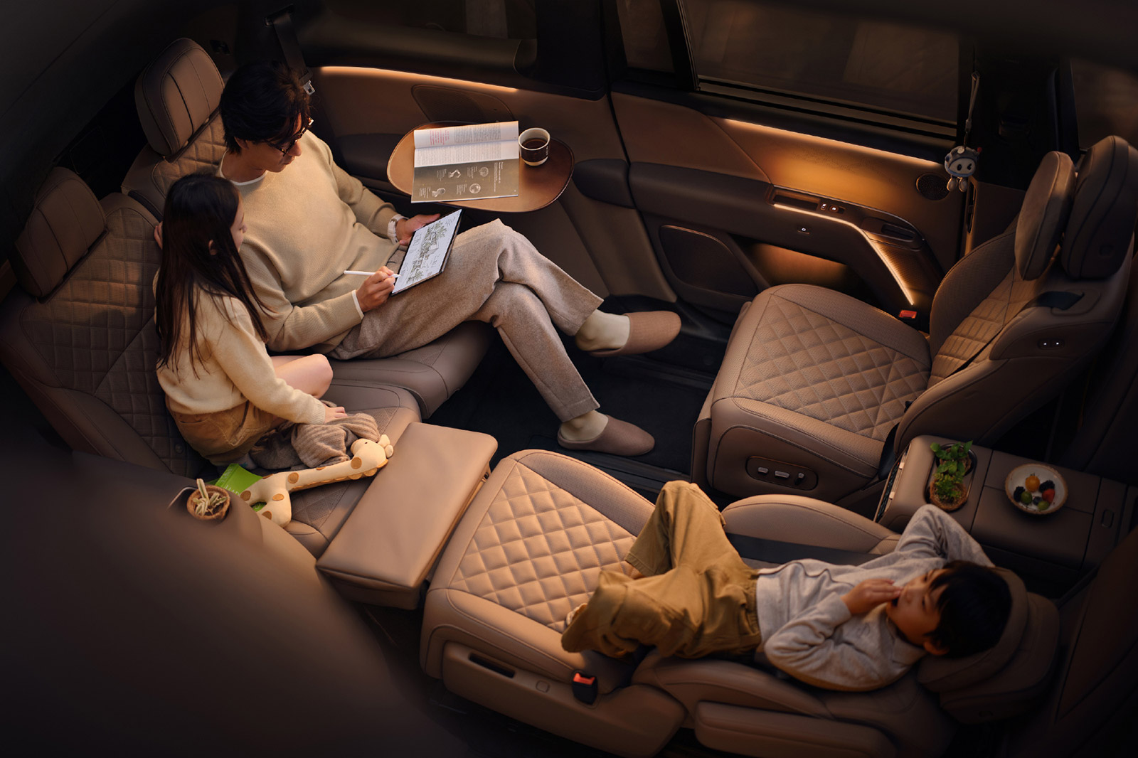 Li i9 Home interior with quilted tan seats arranged face-to-face, a reclining seat, and an adult and 2 children in the cabin.