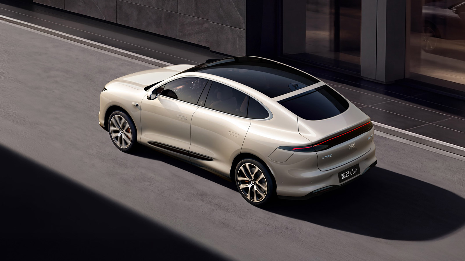 Rear three-quarter view of the updated IM LS6 in champagne beige, showing its panoramic glass roof and full-width taillight.