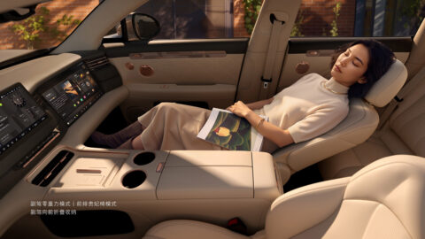 A woman relaxing in the updated IM LS6's reclined front passenger seat with a book on her lap.