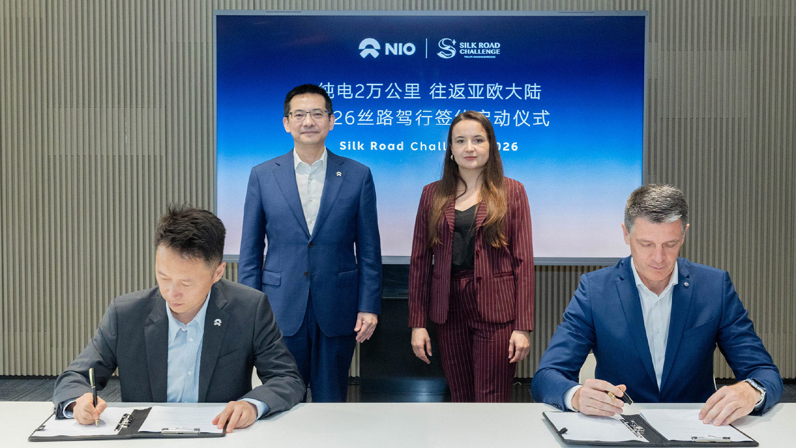 Nio co-founder and president Qin Lihong stands at the back left as representatives sign a cooperation agreement for Silk Road Challenge 2026.