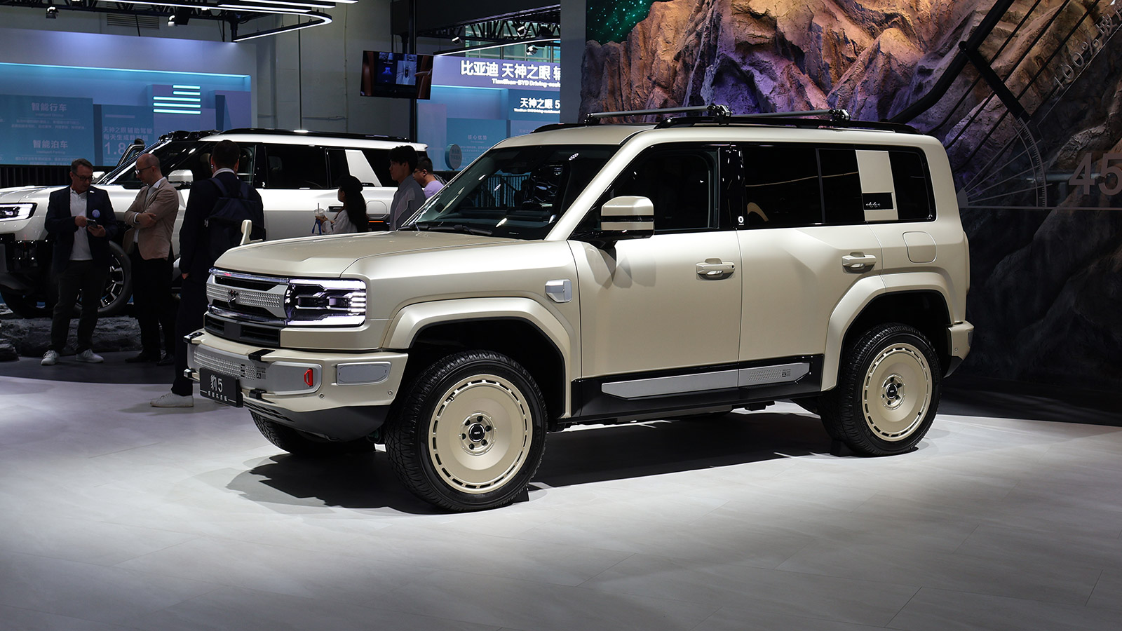 Beige BYD Fang Cheng Bao Bao 5 SUV with a roof rack on display at the 2026 Beijing Auto Show, viewed from the front three-quarter angle.