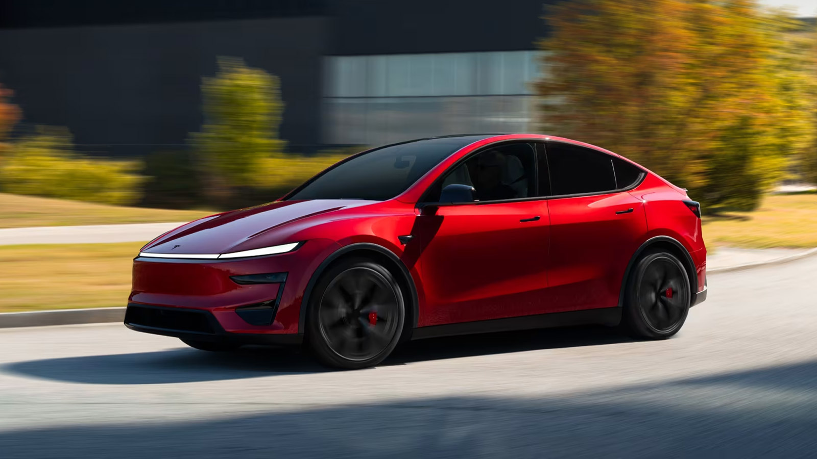 Red Tesla Model Y Performance viewed from the front three-quarter angle, showing its sporty front fascia, dark alloy wheels and red brake calipers.