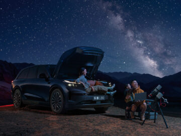 Blue Onvo L80 with its front trunk open beside a family and a telescope under a star-filled night sky.