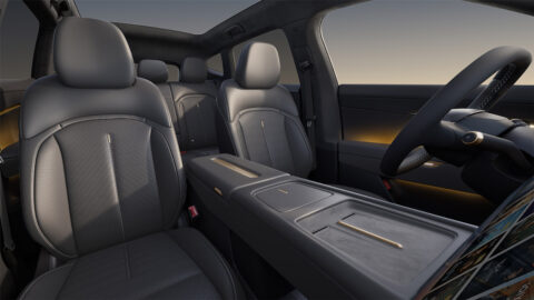Volkswagen ID. UNYX 08 interior showing dark upholstered seats, a wide center console, gold-colored accents and a panoramic glass roof.