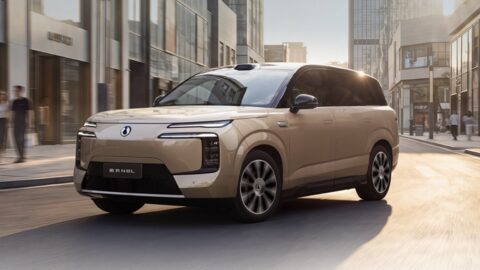 Gold Denza N8L BEV driving along a sunlit city street, showing its front fascia, alloy wheels and roof-mounted LiDAR.