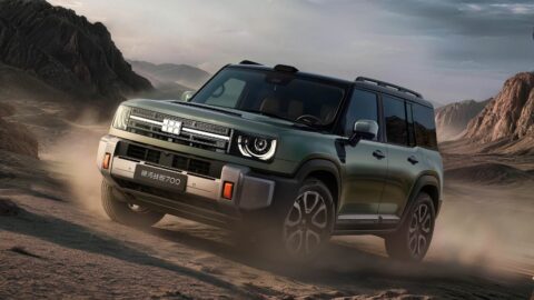 Green Geely Galaxy Cruiser 700 driving across rocky terrain, with dust rising around its wheels and mountains behind it.