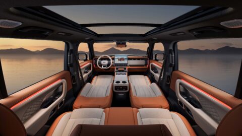 Geely Galaxy Cruiser 700 interior showing reclined front seats, orange-and-cream upholstery, ambient lighting, and a panoramic glass roof.
