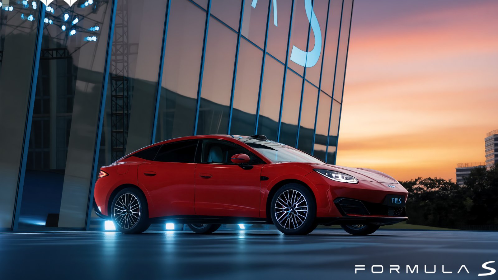Red Fang Cheng Bao Formula S electric sedan parked outside a glass-fronted building at sunset.