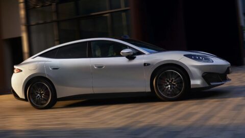 Side view of a silver Fang Cheng Bao Formula S driving past a building.