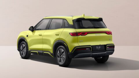 Rear three-quarter view of the yellow 2027 BYD Yuan Up, showing its full-width taillight strip, roof spoiler and black bumper.