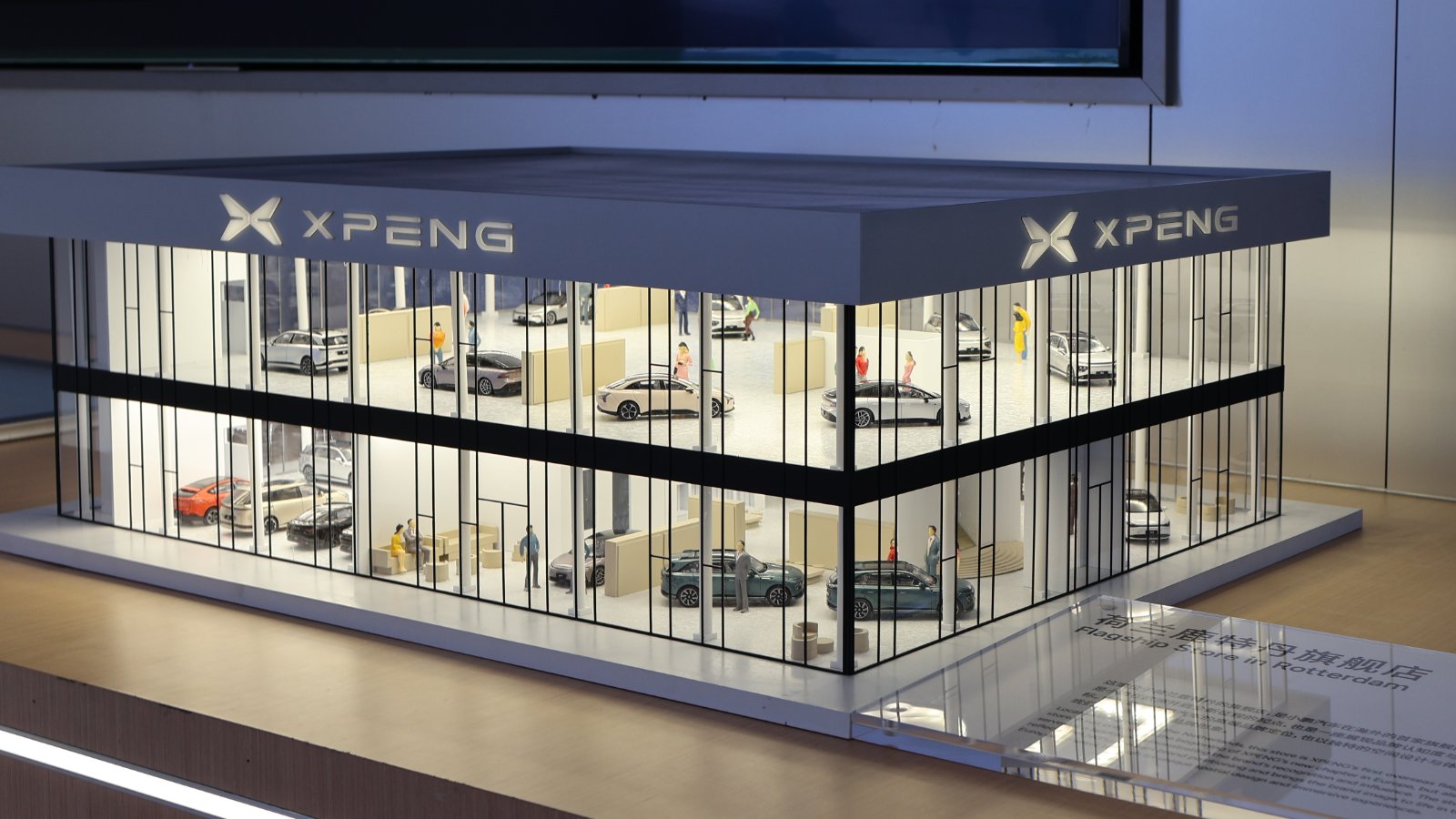 Architectural model of Xpeng's flagship store in the Netherlands, showing a 2-story glass-fronted showroom with miniature vehicles.