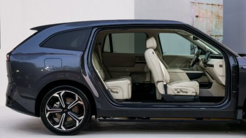 Side cutaway display of a gray Xpeng G9L showing its light-colored front and rear seats, legroom and center console.