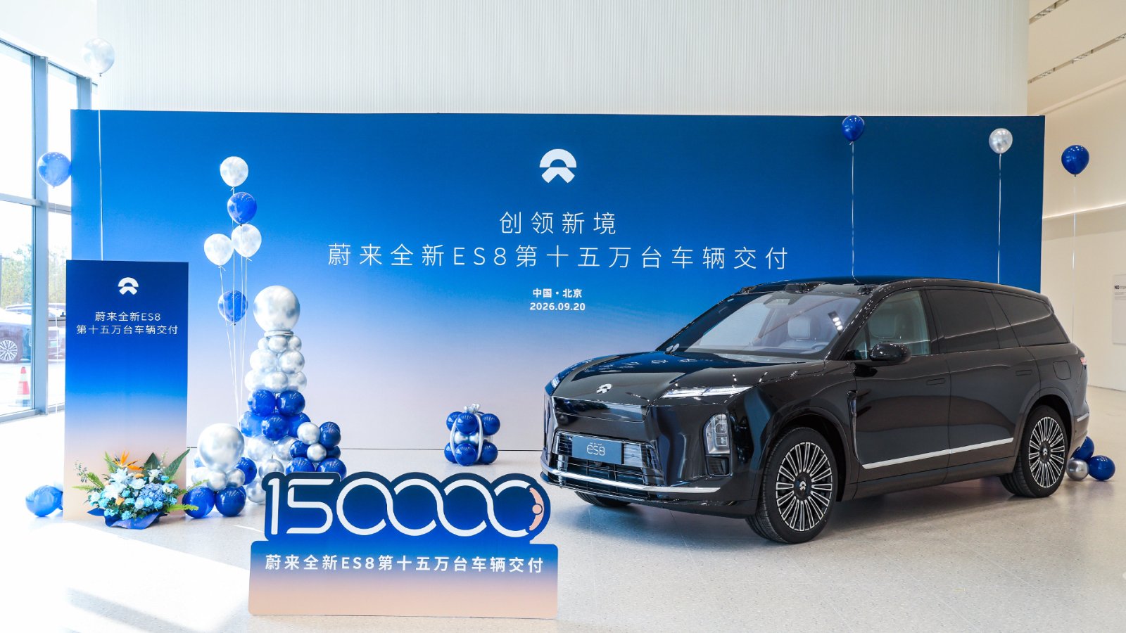 A black Nio third-generation ES8 parked in front of a blue backdrop marking the 150,000th delivery of the model, with a "150000" sign, blue and silver balloons and a bouquet beside it.