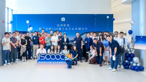 Group photo of Nio staff and ES8 owners in front of a blue backdrop reading "Nio all-new ES8 150,000th vehicle delivery" in Chinese, with a black third-generation ES8 and a large "150000" sign in the foreground.