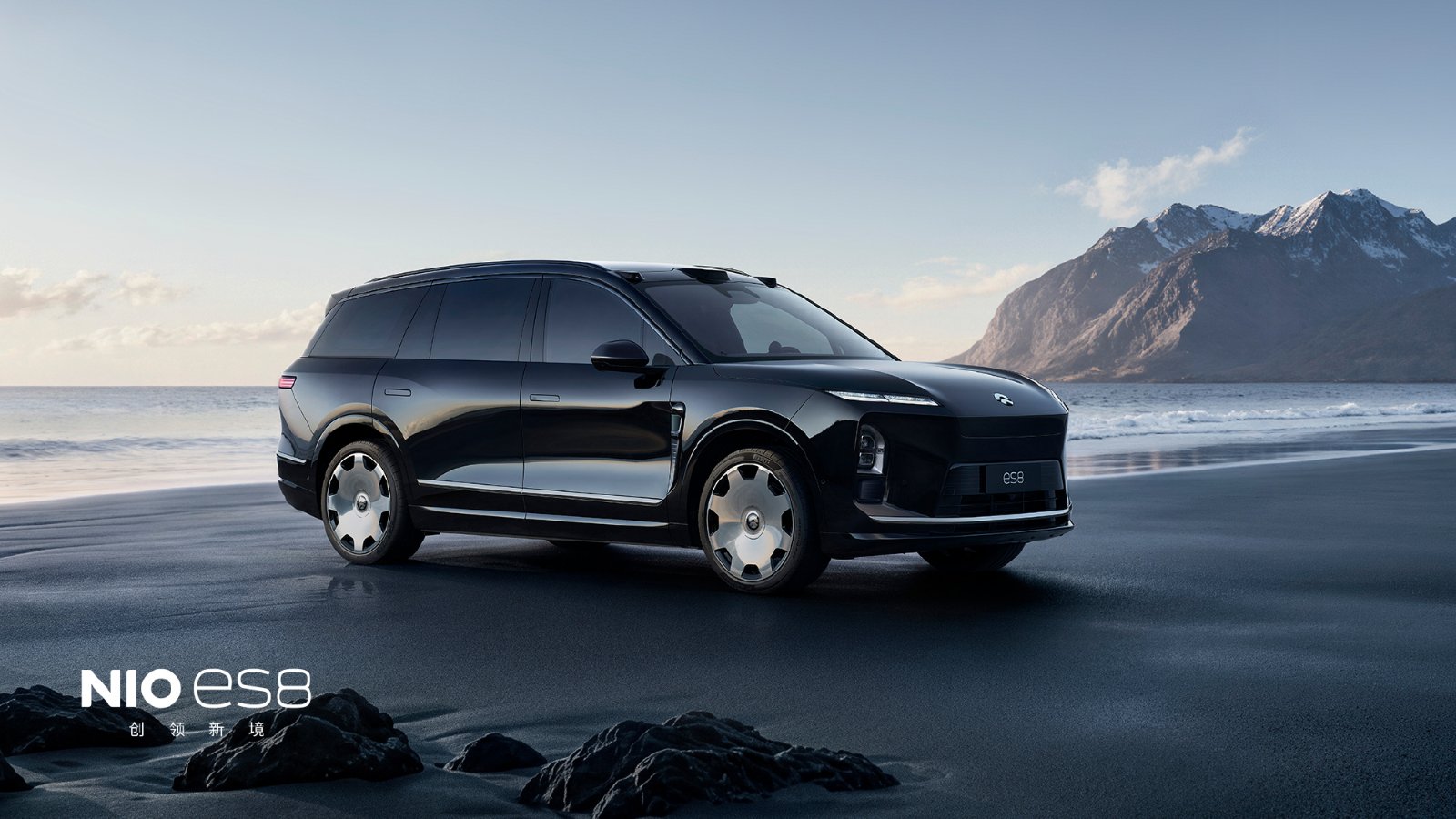Black Nio ES8 with 22-inch Lanyue forged wheels on a beach, with snow-dusted mountains in the background.