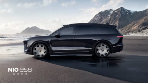 Side profile of a black Nio ES8 featuring silver Lanyue forged wheels against a coastal mountain backdrop.