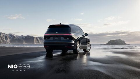 Rear three-quarter view of a black Nio ES8 with Lanyue wheels and an illuminated full-width taillight on a beach.