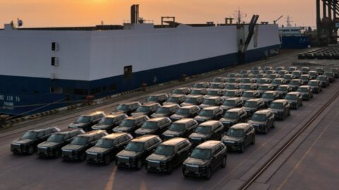 Zeekr 9X SUVs lined up beside a vehicle carrier in warm evening light.