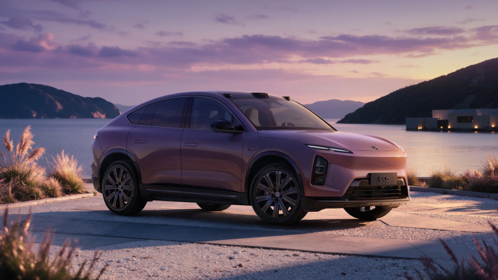 Side profile of the purple Nio EC6 Aura Edition coupe SUV parked by a lake at dusk, showing its 21-inch multi-spoke black wheels and purple brake calipers, with mountains in the background.