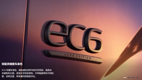 Close-up of the black EC6 badge with an "Aura Edition" nameplate below it on the Aura Purple body panel of the Nio EC6 Aura Edition, with sunset light reflecting off the paint.