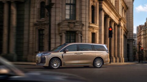 Voyah Dream 9 MPV driving along a city street lined with stone buildings.
