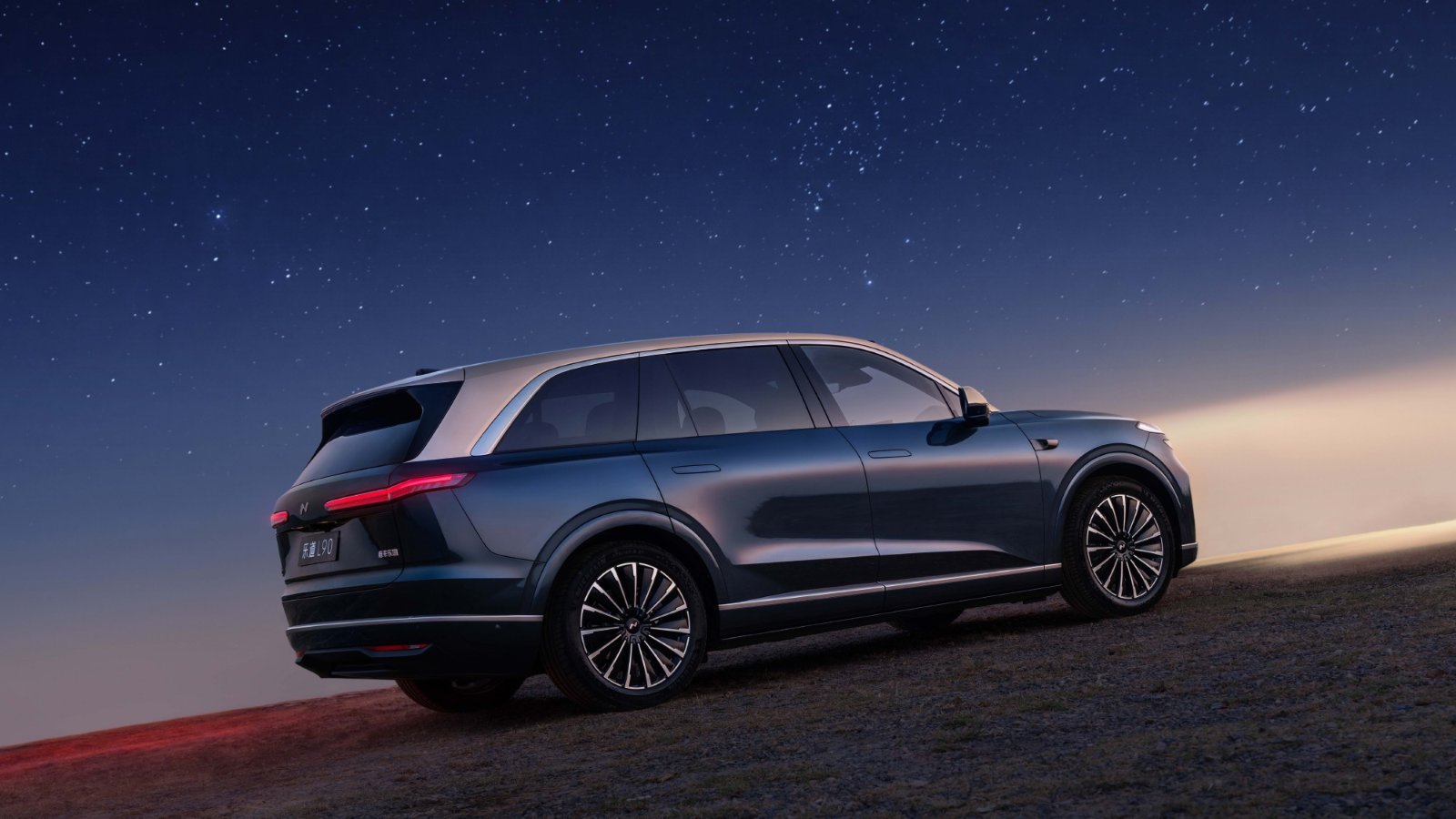 Rear three-quarter view of the Onvo L90 with a Starry Blue and Dawn Gold 2-tone exterior under a starry sky.