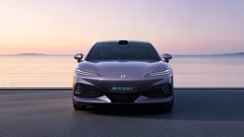 Front view of a purple Denza Z9S electric sedan parked on a coastal road at sunset, showing its slim LED headlights and rooftop lidar.