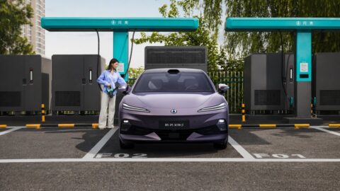 A purple Denza Z9S electric sedan parked at a flash charging station, with a woman standing beside the chargers.