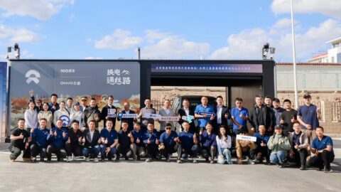 Attendees pose for a group photo outside Nio's Xingxingxia battery swap station at its opening in Xinjiang.