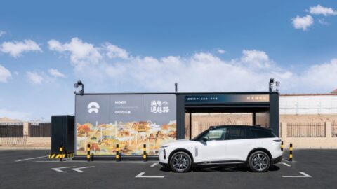 A white SUV parked in front of Nio's Xingxingxia battery swap station, featuring Nio and Onvo branding and a Silk Road mural.